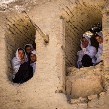 Girls in Afghanistan looking from a house with destroyed windows
