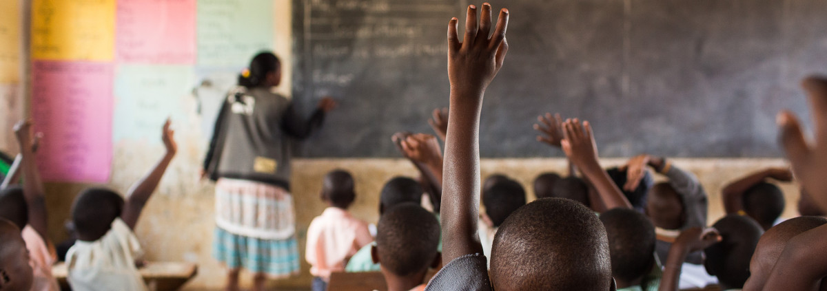 Students raising their hands at a school in Uganda.
