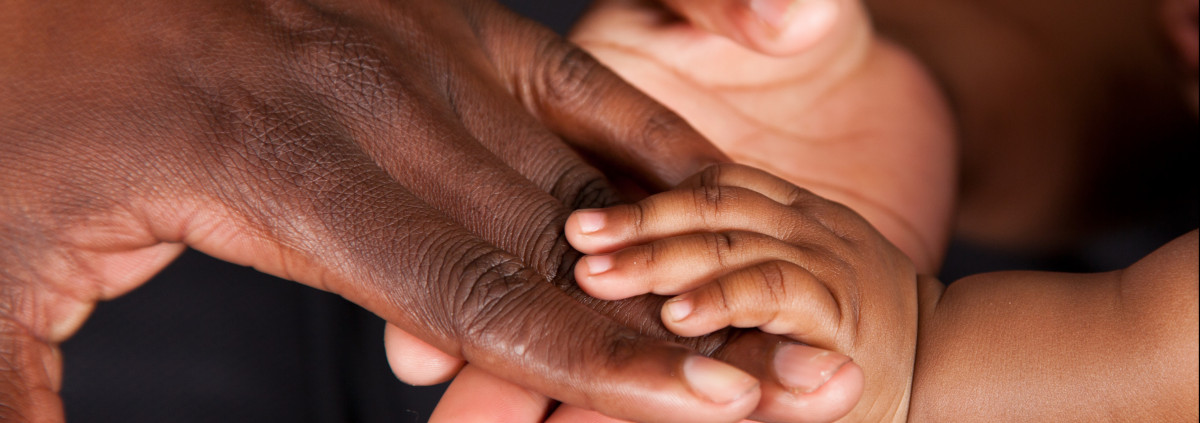 A picture of the hands of a baby, a young person and an older person holding hands
